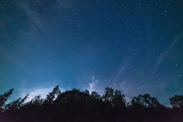 Melkweg en sterrenhemel met onregelmatige wolken langs een steile rots een — Stockfoto