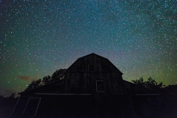 Velhos celeiros com céu estrelado noite com nuvens e forma leitosa — Fotografia de Stock