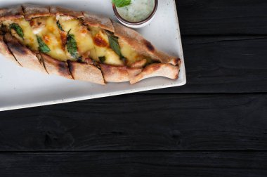 Tekne pasta peynir ve siyah ahşap masa üzerinde ıspanak ile. Gürcü mutfağı. Üstten görünüm. Siyah ahşap arka plan üzerinde. Kopya alanı.