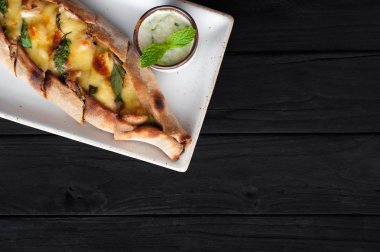 Tekne pasta peynir ve siyah ahşap masa üzerinde ıspanak ile. Gürcü mutfağı. Üstten görünüm. Siyah ahşap arka plan üzerinde. Kopya alanı.