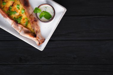 Tekne pasta peynir ve siyah ahşap masa üzerinde ıspanak ile. Gürcü mutfağı. Üstten görünüm. Siyah ahşap arka plan üzerinde. Kopya alanı.