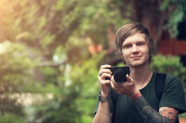 Dijital kamera tutarak ve açık havada gülümseyen yakışıklı delikanlı