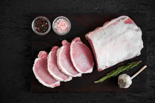 Siyah kesme tahtası üzerinde domuz pirzolası. Yukarıdan görüntülemek