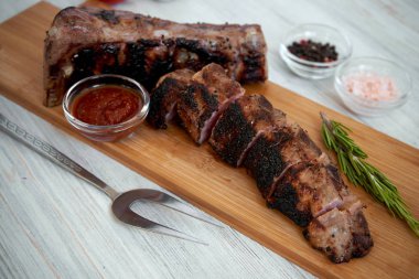 Beyaz zemin üzerinde bir kesme tahtası üzerinde dilimlenmiş Barbekü domuz kaburga ızgara