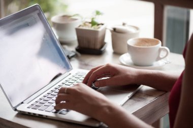 Sarışın genç kadın serbest meslek kafede dizüstü bilgisayar yazmaya