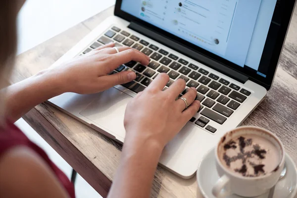 Young blonde woman freelancer typing in laptop in cafe