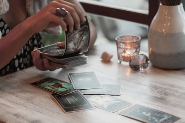 Kadın kafede masada Tarot kartları okuyor.