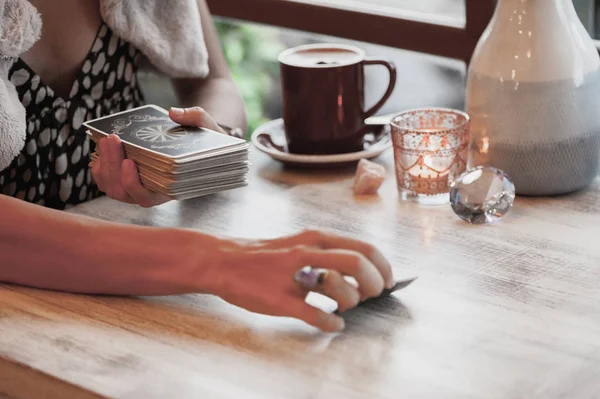 Kadın kafede masada Tarot kartları okuyor.