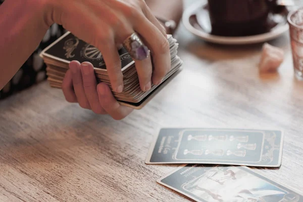 Kadın kafede masada Tarot kartları okuyor.