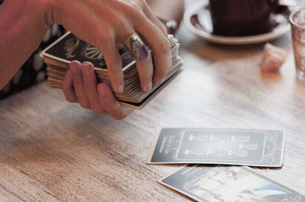 Woman is reading Tarot cards on the table in cafe