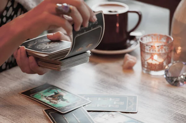 Kadın kafede masada Tarot kartları okuyor.