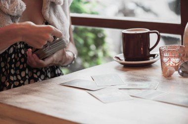 Kadın kafede masada Tarot kartları okuyor.