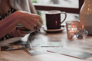 Kadın kafede masada Tarot kartları okuyor.
