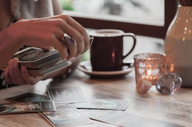 Kadın kafede masada Tarot kartları okuyor.