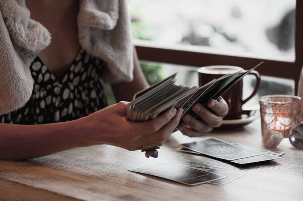 Woman is reading Tarot cards on the table in cafe