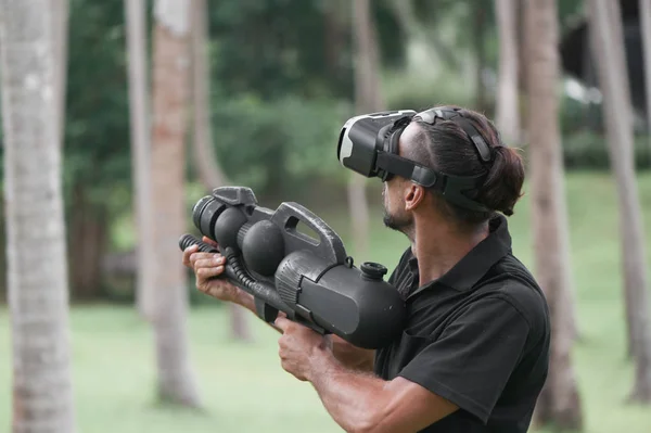 Man in virtual reality headset playing video game among palm trees