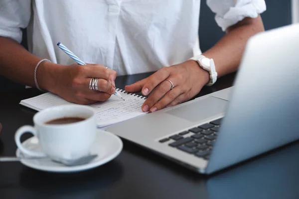 Kafe ve not defterindeki not almak oturan genç iş kadını.