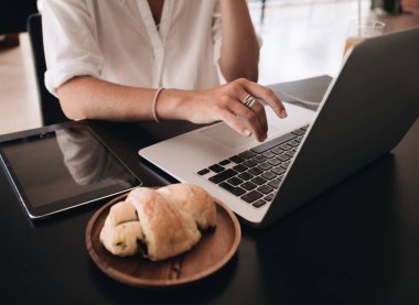 Genç kadın öğrenci kafede oturan ve kahvaltı laptop ile çalışan dizüstü bilgisayar ile