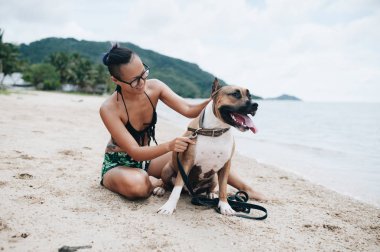 Oturma ve onun köpeği kumsalda sarılma eyeglases neşeli genç ve güzel kadın