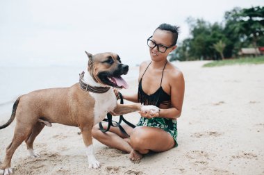 Oturma ve onun köpeği kumsalda sarılma eyeglases neşeli genç ve güzel kadın