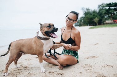 Oturma ve onun köpeği kumsalda sarılma eyeglases neşeli genç ve güzel kadın
