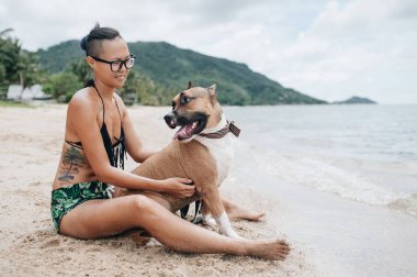 Oturma ve onun köpeği kumsalda sarılma eyeglases neşeli genç ve güzel kadın