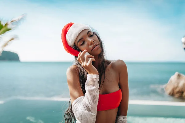 サンタさんの帽子で美しい女性のプライベートのヴィラのプールサイドで楽しくしています — ストック写真