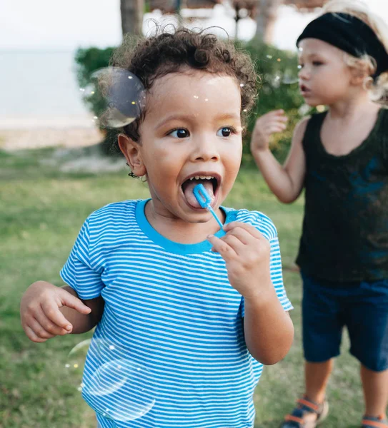 Little boys with soap bubbles in tropical garden — Stock Photo, Image