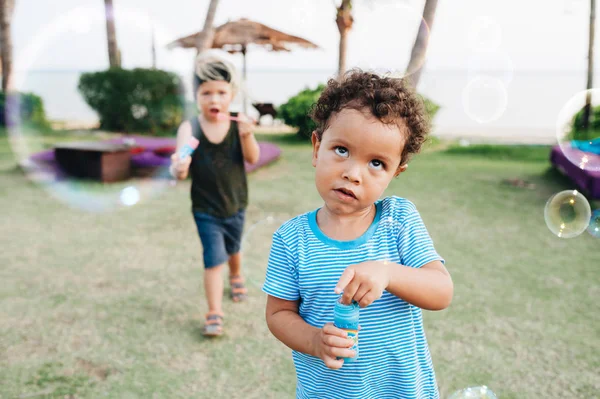 Little boys with soap bubbles in tropical garden — Stock Photo, Image