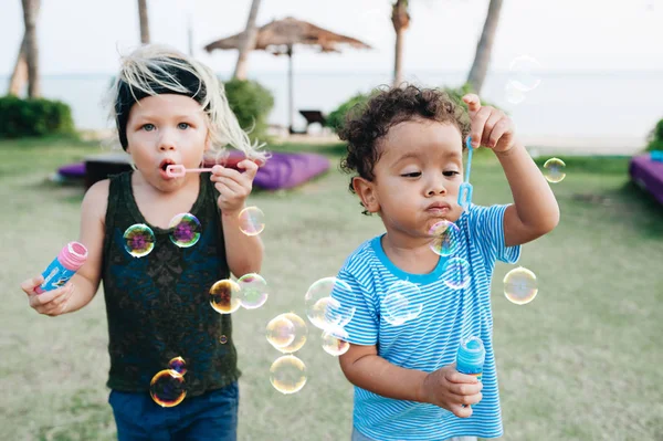 Little boys with soap bubbles in tropical garden — Stock Photo, Image