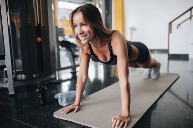 Çekici genç kadın spor salonunda tahta egzersiz yapıyor