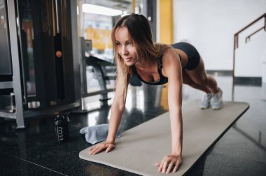 Çekici genç kadın spor salonunda tahta egzersiz yapıyor