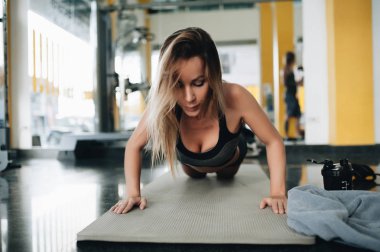 Çekici genç kadın spor salonunda tahta egzersiz yapıyor