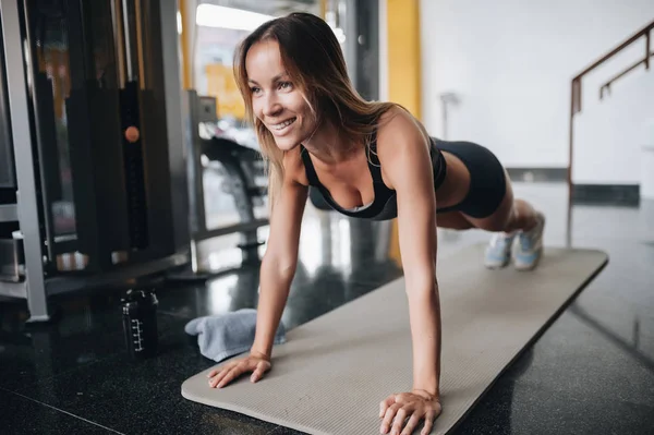 Attrayant jeune femme fait de l'exercice de planche dans la salle de gym — Photo