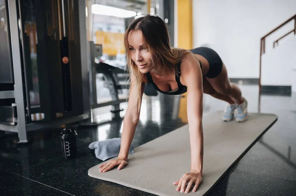 Atractiva joven mujer está haciendo ejercicio tablón en el gimnasio —  Fotos de Stock