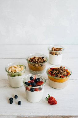 Beyaz arka planda yoğurt, granola ve farklı MEYVELERLE kase