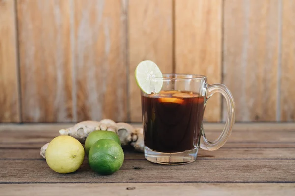 Świeża zimna herbata z limonką, miętową i cytrynową na drewnianym stole — Zdjęcie stockowe