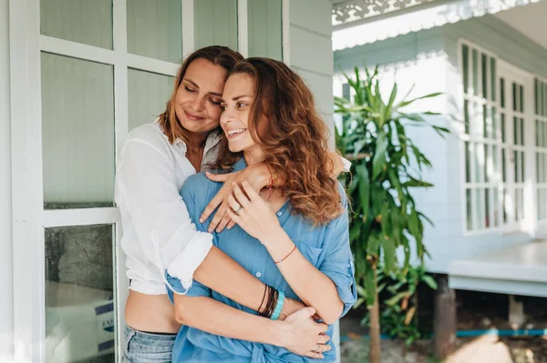 Feliz pareja de lesbianas de pie en la terraza de su casa de campo —  Fotos de Stock