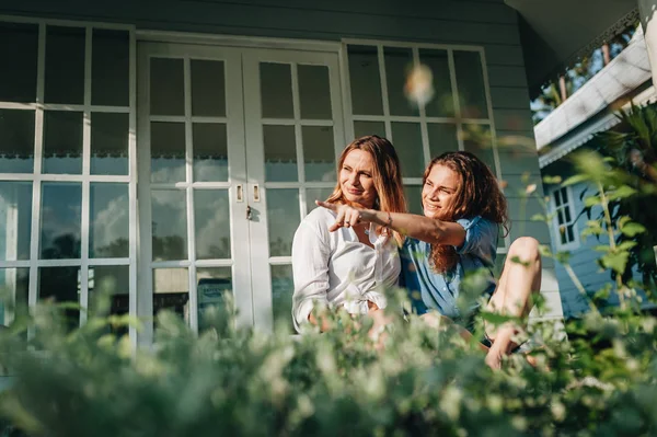 Счастливая лесбийская пара, сидящая на террасе в своем загородном доме — стоковое фото