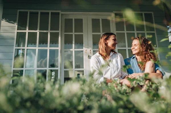 Gelukkig lesbisch paar zittend op terras in hun landhuis — Stockfoto