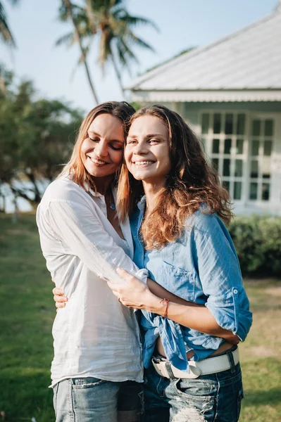 Gelukkige lesbische paar knuffelen in de tuin in hun landhuis — Stockfoto