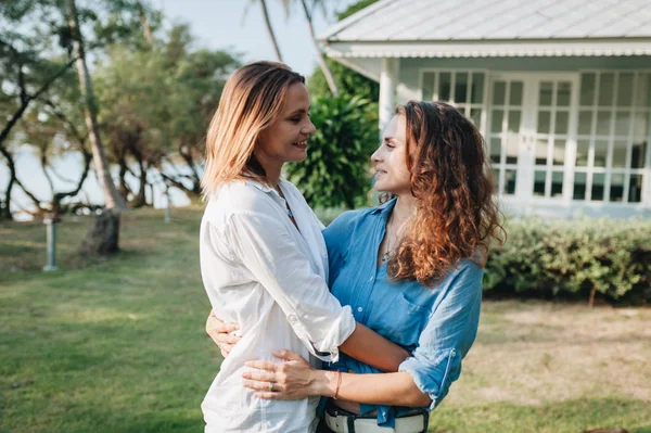 Felice coppia lesbica abbracciare in giardino presso la loro casa di campagna — Foto Stock
