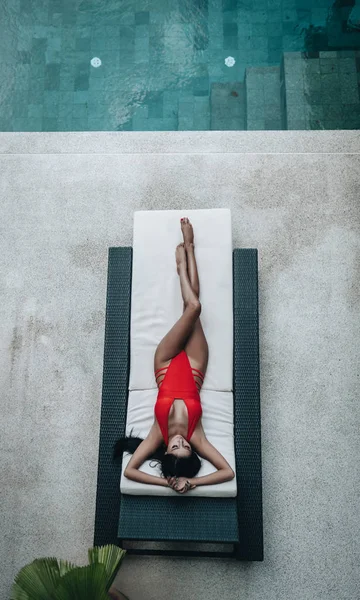 Sexy femme asiatique dans un maillot de bain rouge posé dans un transat au bord de la piscine — Photo