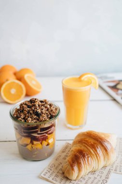 Masada lezzetli bir kahvaltı. Beyaz masada taze portakal suyu, meyve salatası ve kruvasan.