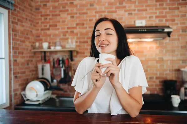 Jong gelukkig vrouw drinken koffie op de keuken in de ochtend. — Stockfoto