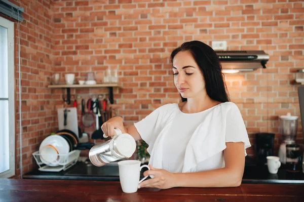 Jovem mulher feliz bebendo café na cozinha pela manhã. — Fotografia de Stock