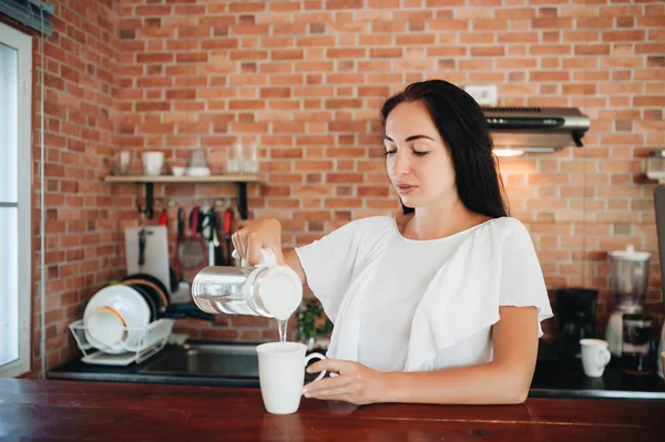 Jong gelukkig vrouw drinken koffie op de keuken in de ochtend. — Stockfoto