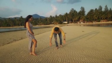 Genç çift gün batımında tropikal bir plajda eğlenmek.