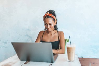 Kafede dizüstü bilgisayarı ve kahvesiyle çalışan Asyalı kadın