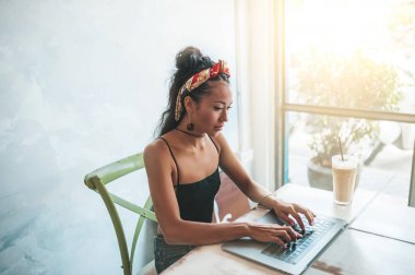 Kafede dizüstü bilgisayarı ve kahvesiyle çalışan Asyalı kadın